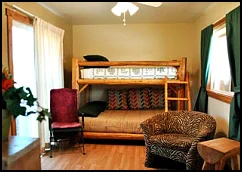 Homey sitting room with log-style bunk bed and zebra-striped chair in the Sunflower Suite