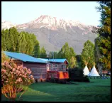 View of the Red Rooster Suite’s private deck, lush lawn, tepees and mountain views